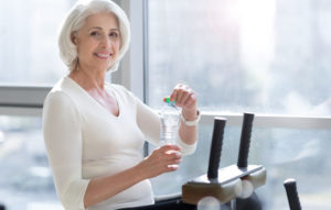 Joyful fit senior woman drinking water during workout. Medicare Part D Colorado